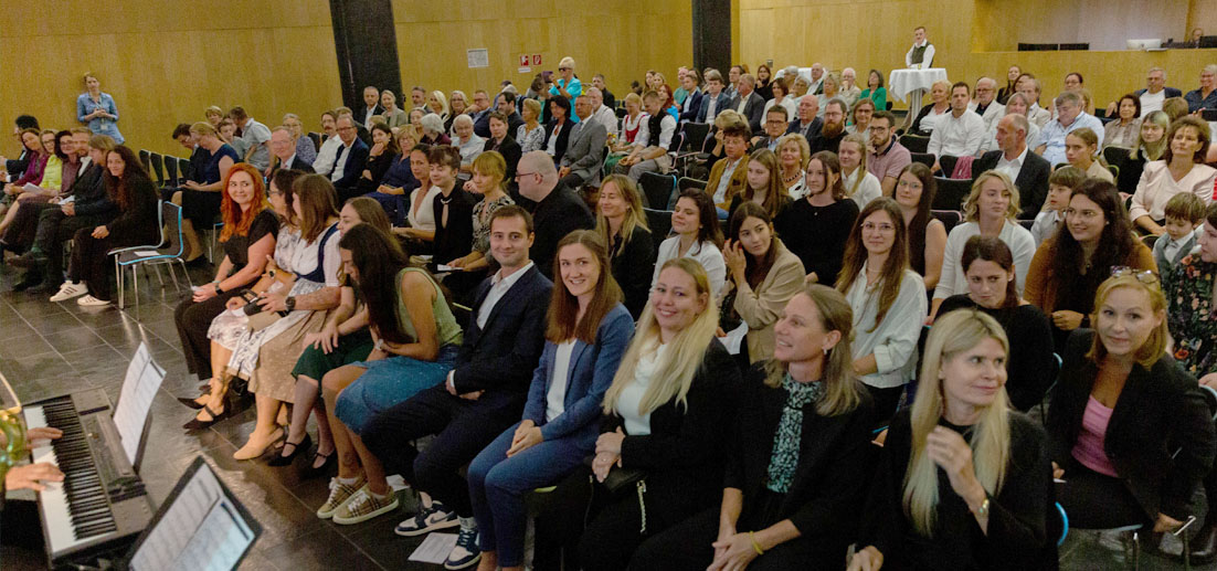 Das Bild zeigt die feierliche Stimmung während der Sponsionsfeier: Im rechten vorderen Bereich sitzen die Absolventinnen und Absolventen, umgeben von Ehrengästen, Familien, Freundinnen und Freunden sowie Lehrenden und Mitarbeitende des Studienservices.