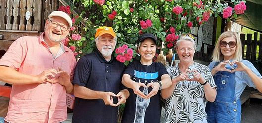 Das Bild zeigt insgesamt fünf Vortragende des ARS Summer Camp. Im Hintergrund sind Blumen zu sehen. 