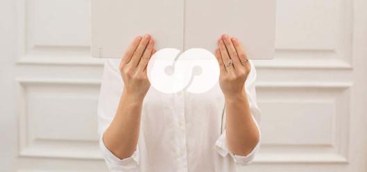 Zwei Hände halten ein Buch. Das Bild ist in hellen Farben gehalten, überwiegend in Weiß.