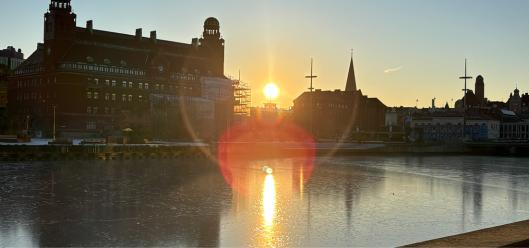 Gebäude in Malmö am Flussufer im Sonnenuntergang mit Spiegelungen im Wasser.