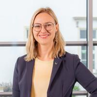 Porträt einer Frau mit schulterlangen blonden Haaren und Brille. Sie lächelt freundlich in die Kamera.