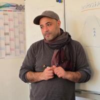 Ali Sina Farahmandnia staht vor einem Whiteboard und trägt eine Kappe und einen grauen Pullover.