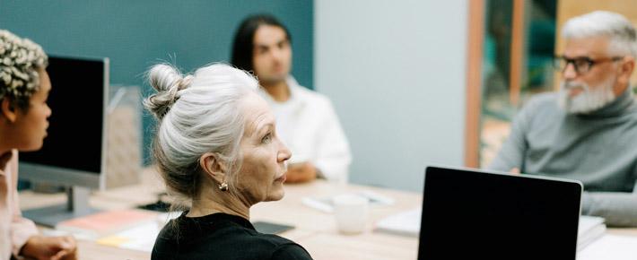 Vier Menschen bei Besprechung an Tisch sitzend