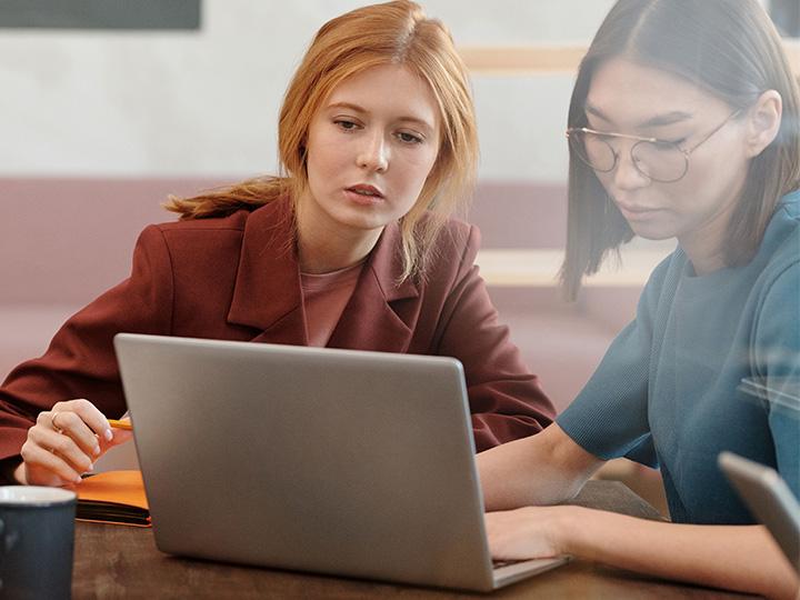 Zwei Studierende sitzen nebeneinander, arbeiten gemeinsam am Laptop und betrachten den Bildschirm (c) pexels-diva-plavalaguna