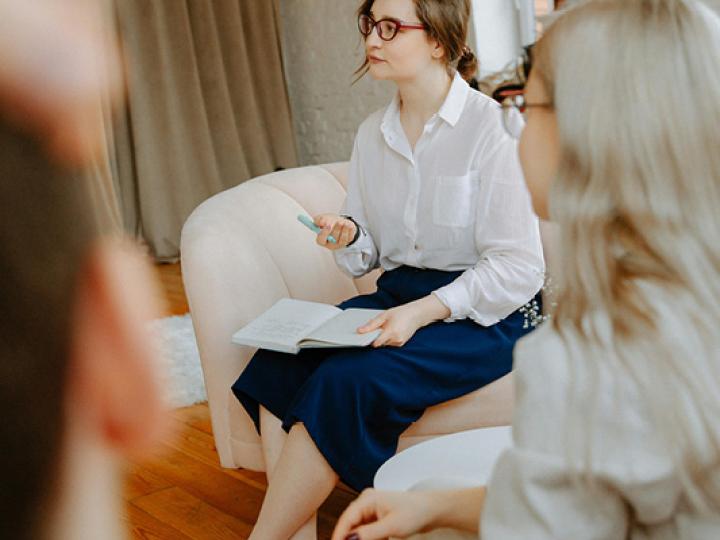 Frau mit Notizheft und Stift im Mittelpunkt einer Peergruppe (C) pexels_polina-zimmerman