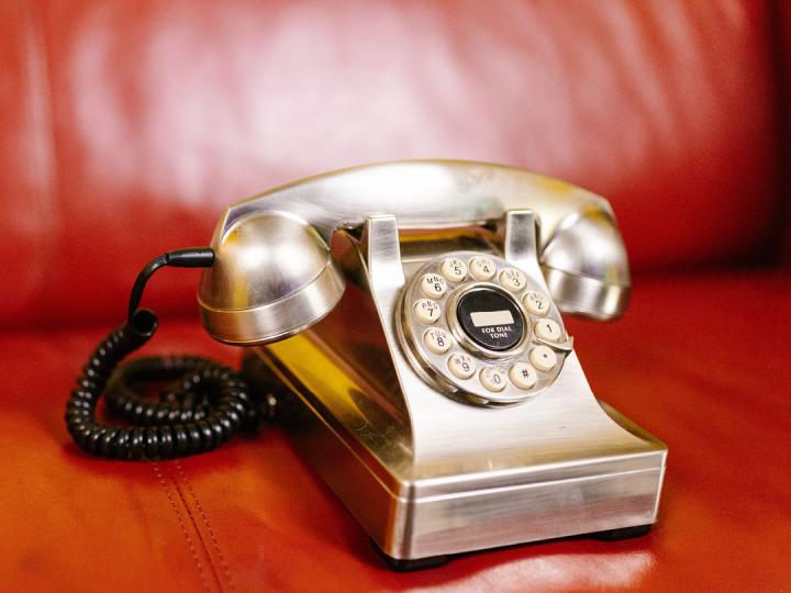 Silbernes Telefon mit Hörer auf orangefarbener Ledercouch (c) pexels_rdne